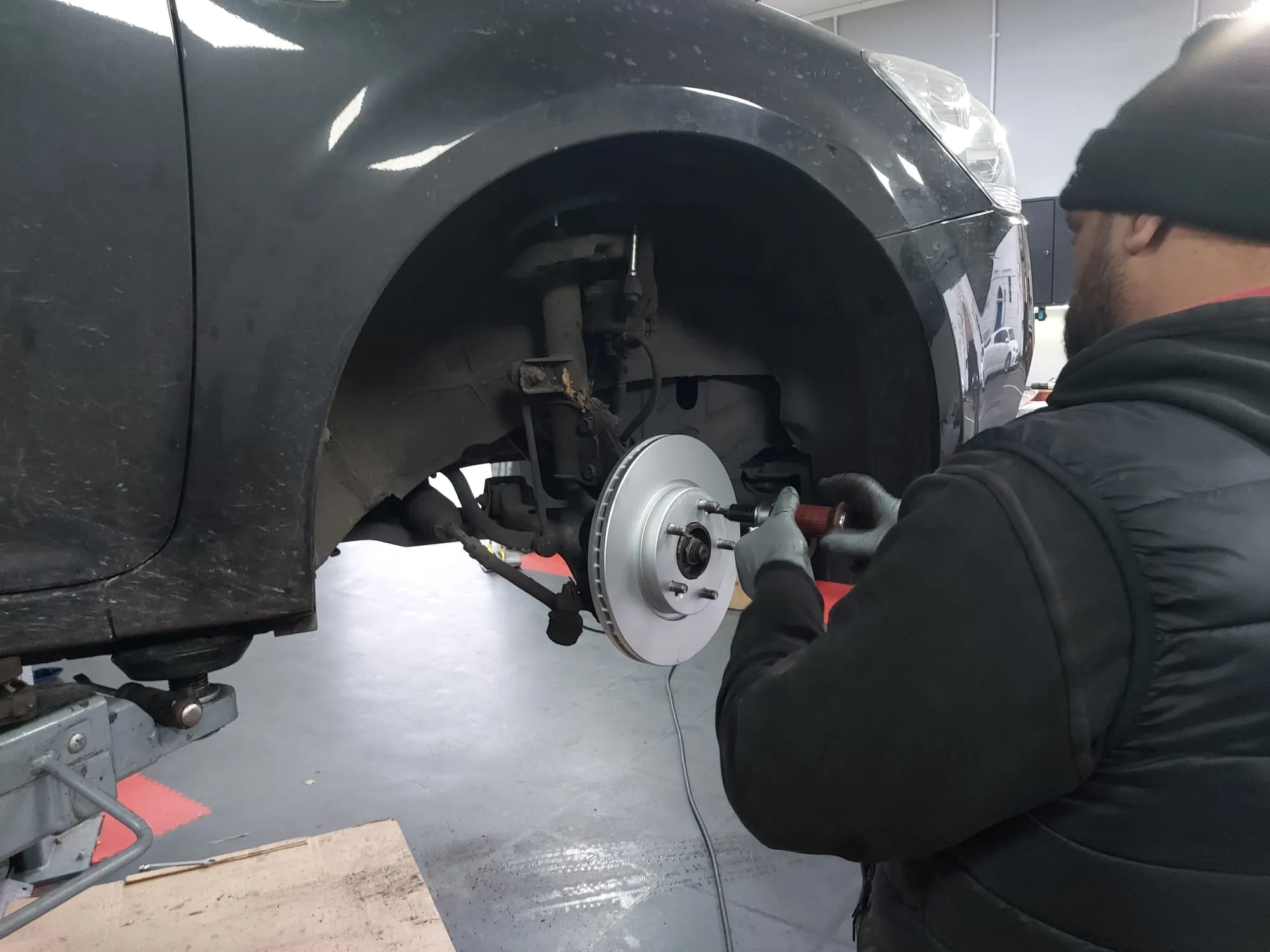 Man servicing a car with wheel removed